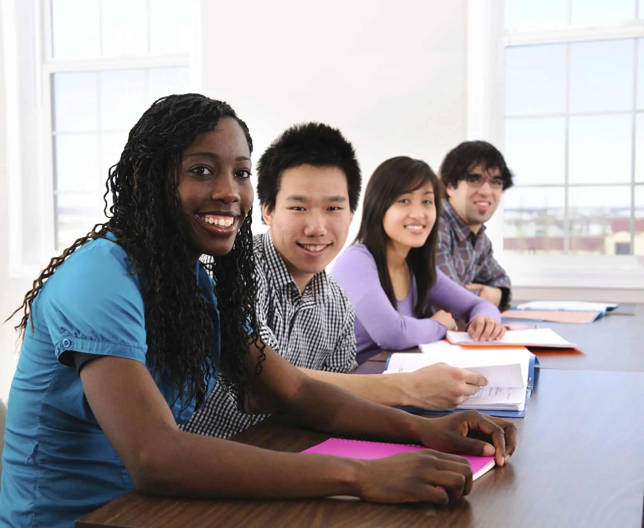Diverse students sitting together and smiling in a classroom.