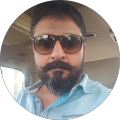 Man with sunglasses and beard in car.